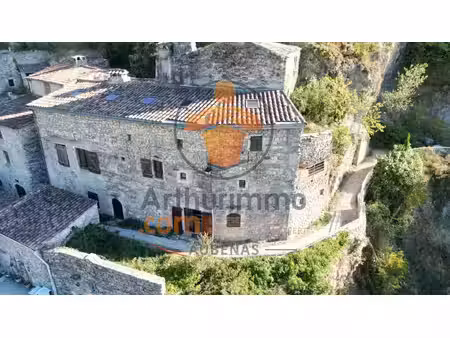 une maison de pierre suspendue au-dessus des collines  à rochecolombe
