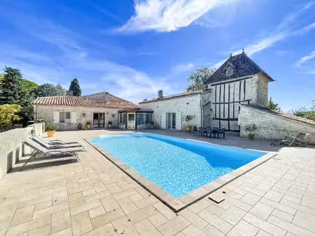une maison en pierres autour de sa piscine